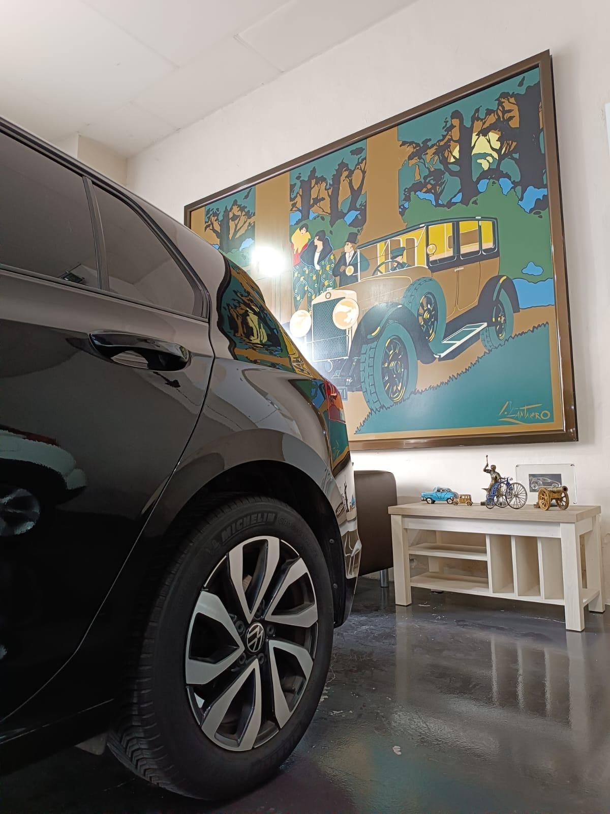 Exposición de Mi Tienda de Coches en Lucena, con un coche y el gran cuadro de un automóvil clásico
