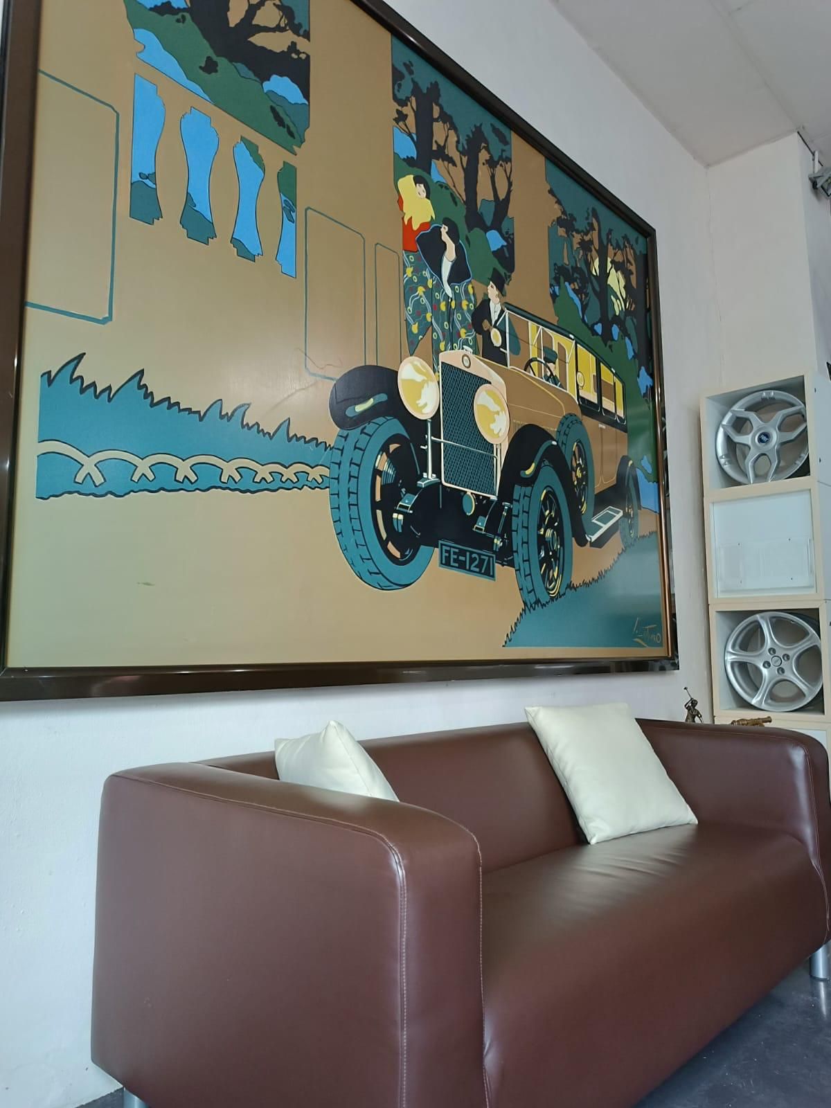 Zona de espera del local con sofá y gran cuadro de un coche clásico